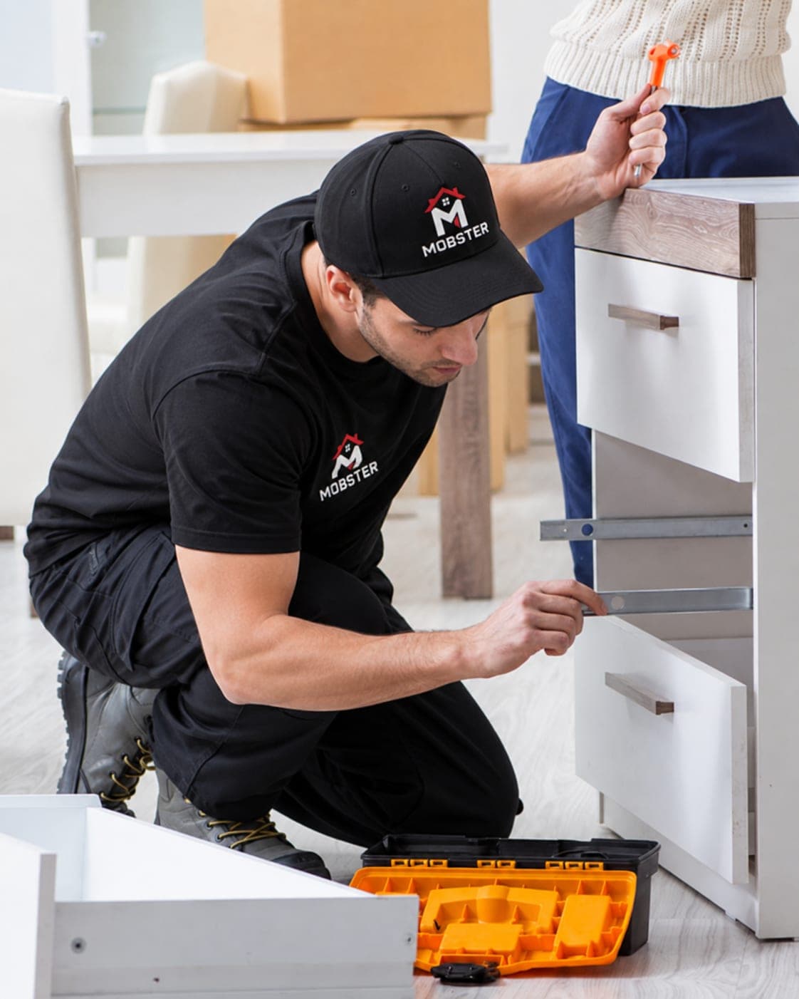 A Mobster fitting drawer slides while assembling a white dresser
