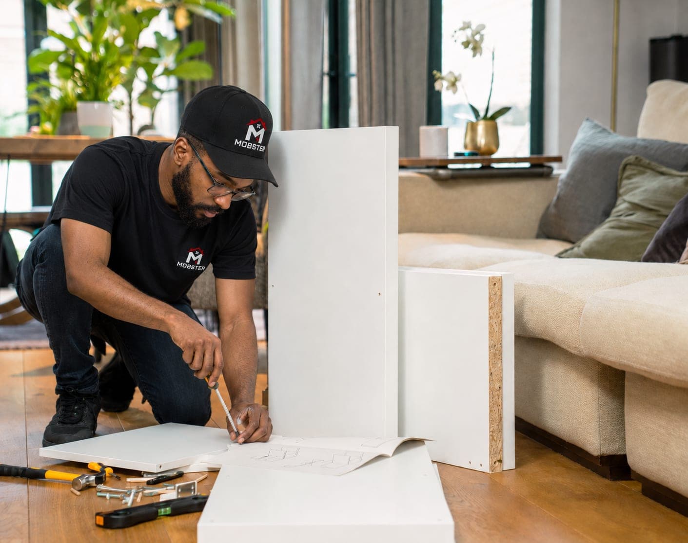 A Mobster marking up flat-pack panels against the instructions in a living room