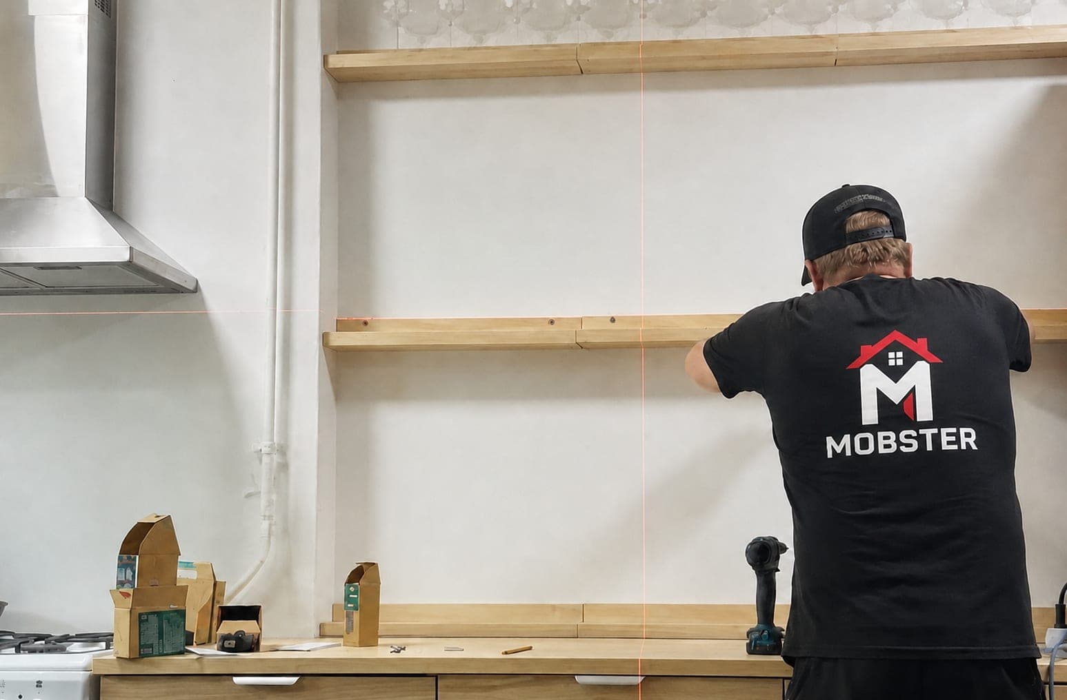 A Mobster levelling floating kitchen shelves with a laser line