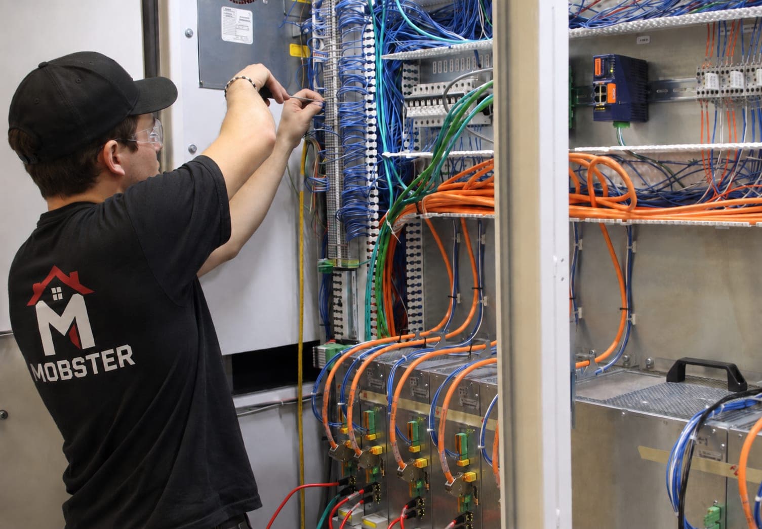 A Mobster routing patch cables inside a structured network cabinet